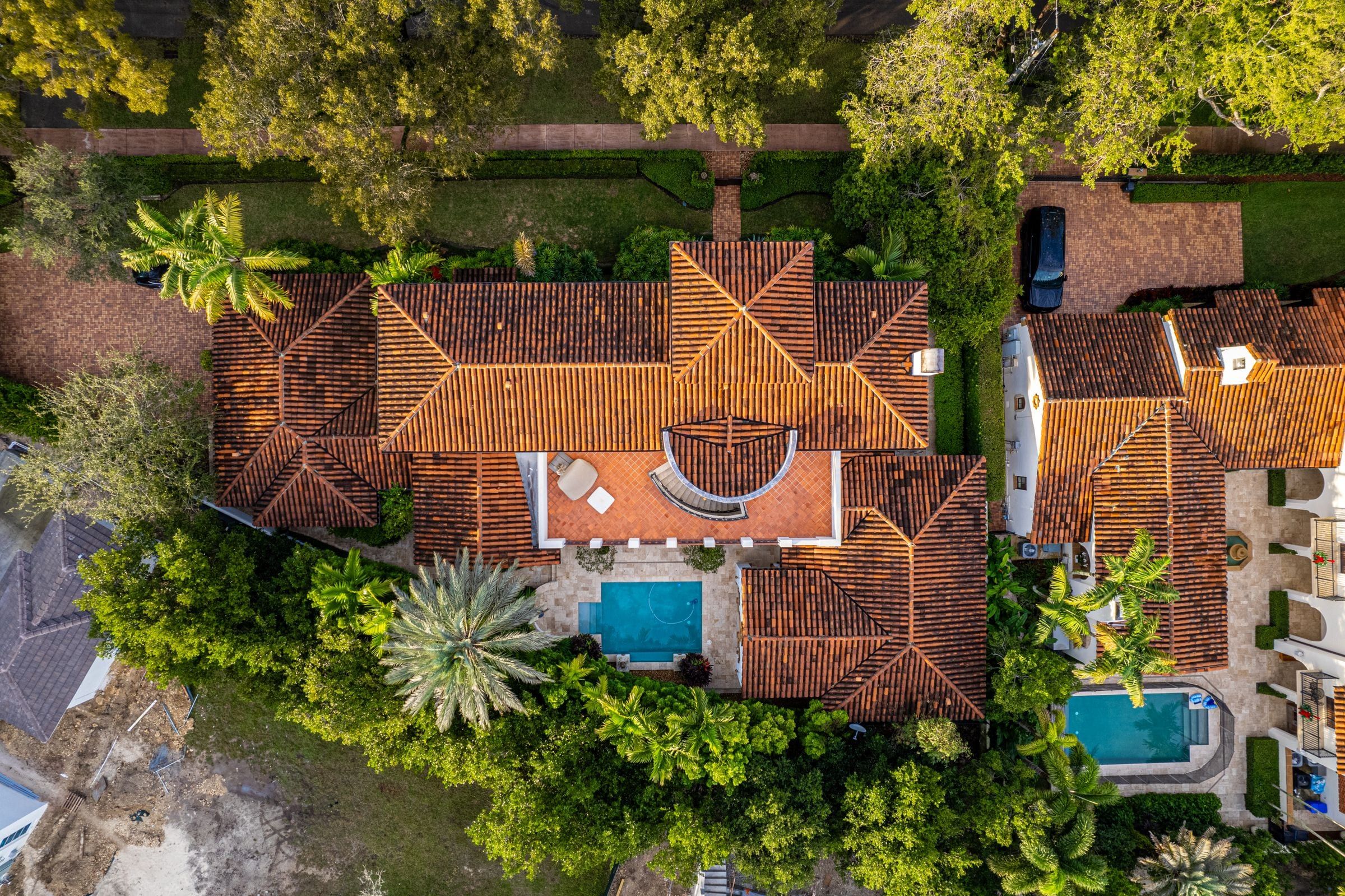 Aerial view of tile-roof homes with pools and palm trees in a Florida neighborhood