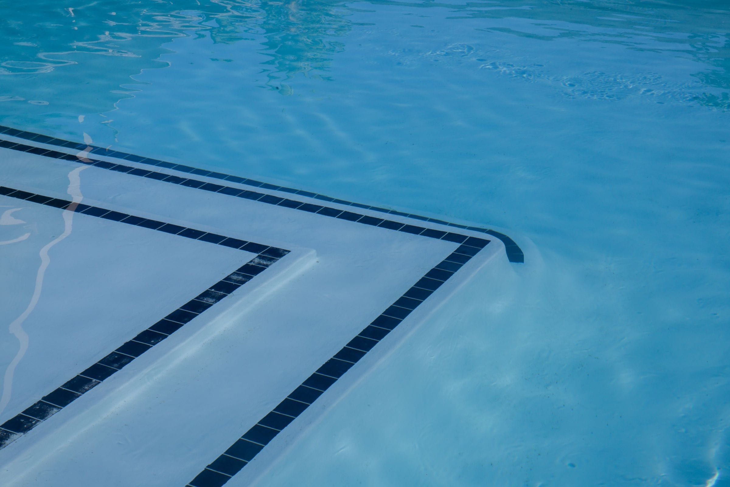 Pool steps outlined with dark blue tile in clear water